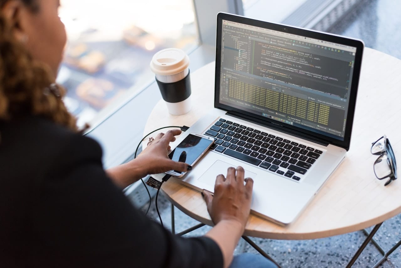 Un enginyer d'Unimedia treballant entre una app mòbil i el seu codi de backend