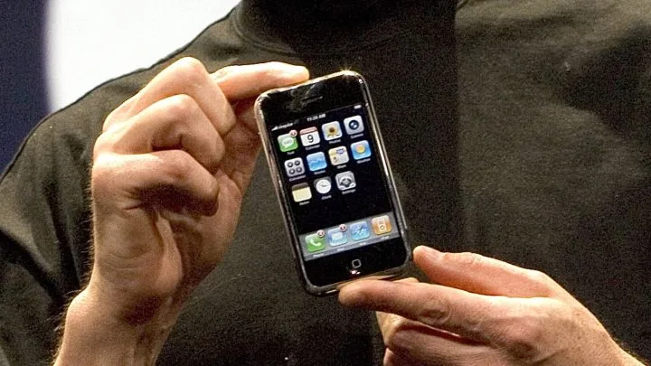 Una mà sosté el primer iPhone, amb la pantalla d’inici plena d’icones d’aplicacions