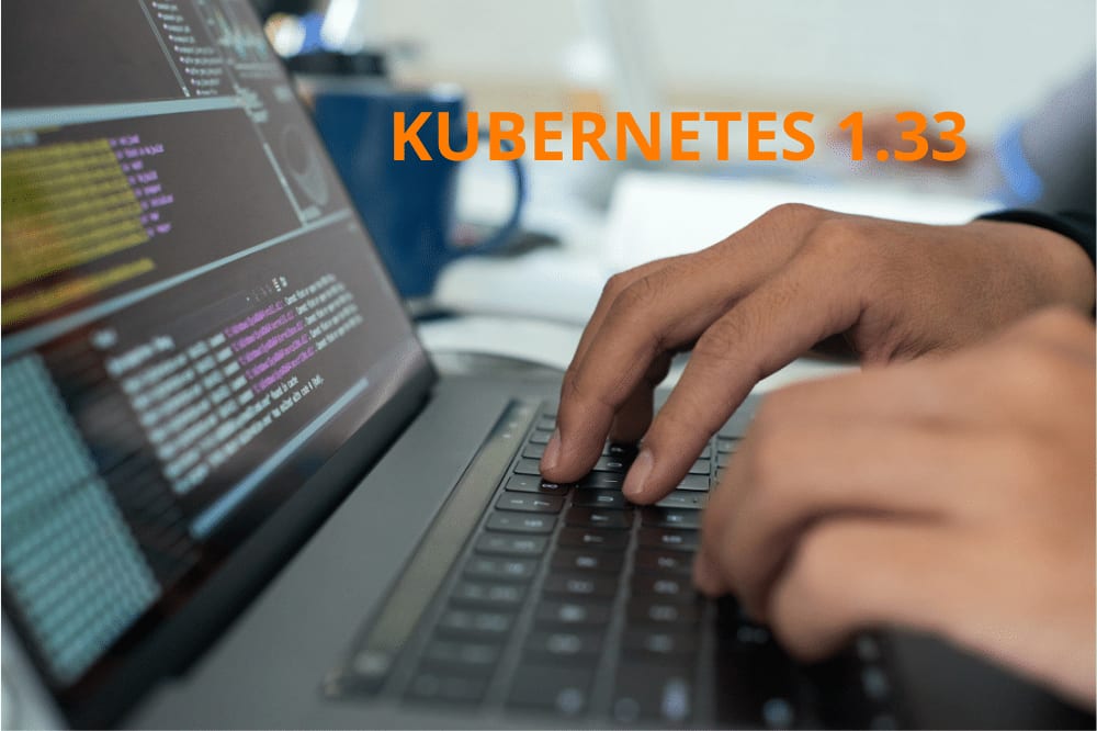 Unas manos teclean en un portátil que muestra un terminal, con el rótulo «Kubernetes 1.33»